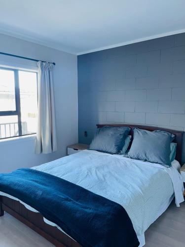 a blue bedroom with a bed with blue sheets and a window at Sunny Tidy Corner in Ellerslie in Auckland