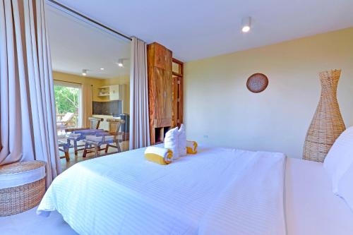 a bedroom with a white bed and a dining room at Boracay Amor Apartment in Boracay