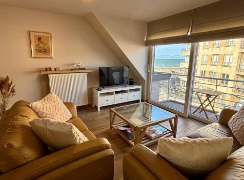 een woonkamer met 2 banken en een televisie bij Zen at Sea Duplex Blankenberge in Blankenberge