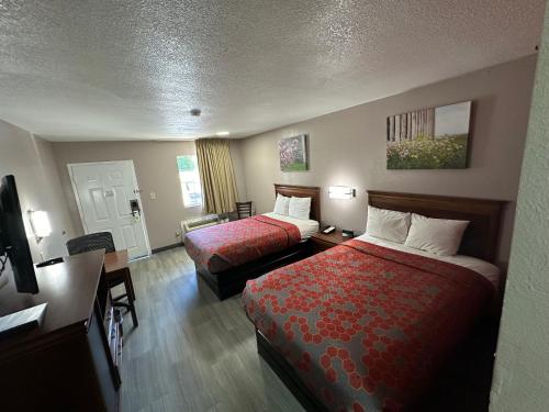 een hotelkamer met twee bedden en een bureau bij The Heritage Inn, Inc in Huntingdon