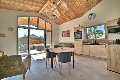 Una cocina y un comedor con mesa y sillas. en L Etel - spa extérieur vue étoiles de la chambre et vélos électriques, en Mortagne-sur-Gironde