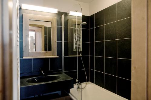 La salle de bains est pourvue d'un lavabo, d'un miroir et d'une baignoire. dans l'établissement Résidence Les Grandes Feignes, à La Bresse