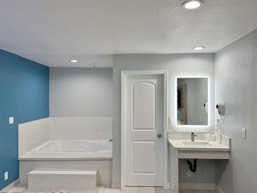 ローズミードにあるRoyale Inn - San Gabriel, Los Angelesの浴槽と洗面台と白いドアのあるバスルーム
