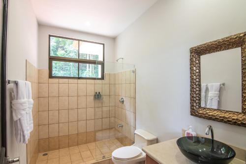 a bathroom with a shower and a sink and a mirror at Villa Montana in Tarcoles