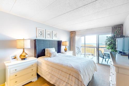 a bedroom with a bed and a television and a balcony at Triton's Trumpet B 303 in Ocean City