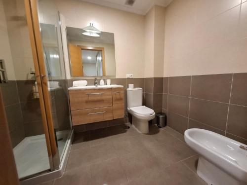 a bathroom with a toilet and a sink and a mirror at APARTAMENTO PLAYA FOZ in Foz