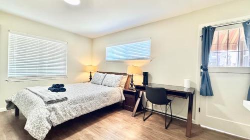 een slaapkamer met een bed en een bureau en twee ramen bij Remodeled Bungalow Suite with Parking, Steps from SJSU in San Jose