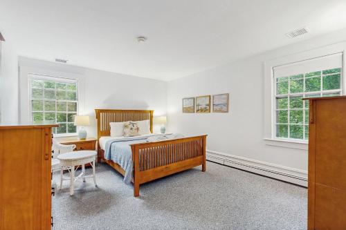 a bedroom with a bed and a desk and two windows at Cozy Corner in Edgartown