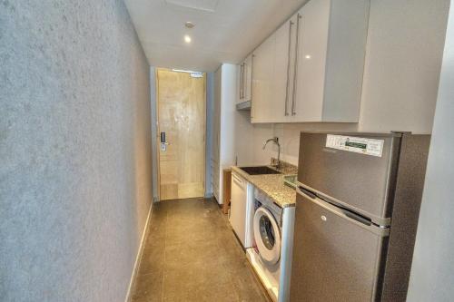 a small kitchen with a refrigerator and a dishwasher at Luxury Vacation Home Nr Metro DWTC in Dubai