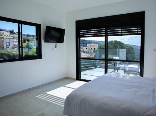 a bedroom with a bed and a balcony with a television at Vista royal golan in Ein Kinya