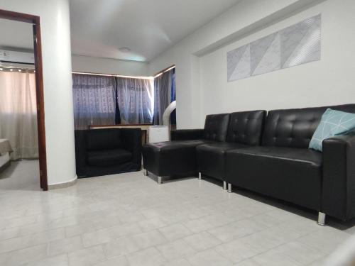 een woonkamer met een zwarte leren bank en stoelen bij Apartamento con vista al Mar bien ubicado 