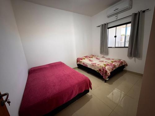 a small bedroom with a bed and a window at Casinha Aconchegante in Primavera do Leste