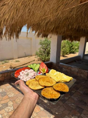 a person holding a tray with food on a table at Miral Camp in Nuweiba