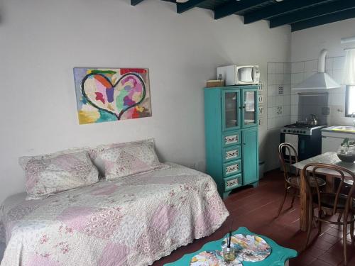 a bedroom with a bed and a kitchen with a table at La Casita in Neuquén