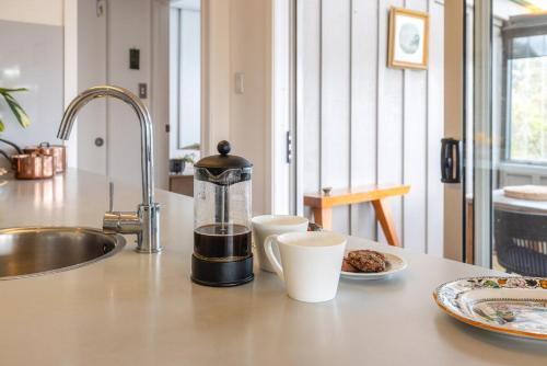 a kitchen counter with a coffee maker and a plate of food at Waters Edge by Waiheke Pure in Waiheke Island