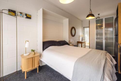 a bedroom with a white bed and a table with a lamp at Waters Edge by Waiheke Pure in Waiheke Island