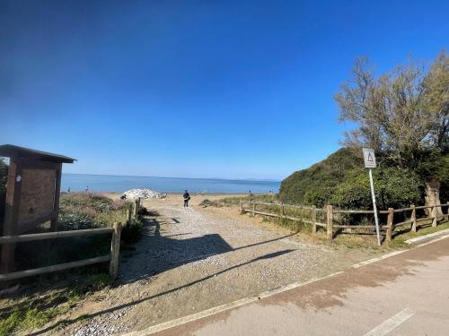 a person walking down a dirt road near the beach at Lovely apartment near the beach in Follonica