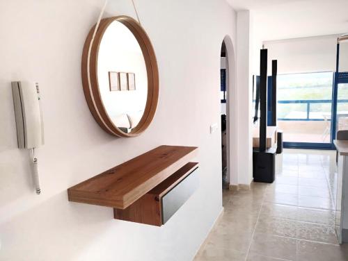 a mirror on a wall with a wooden bench in a room at Dream apartment in Isla Plana in Mazarrón