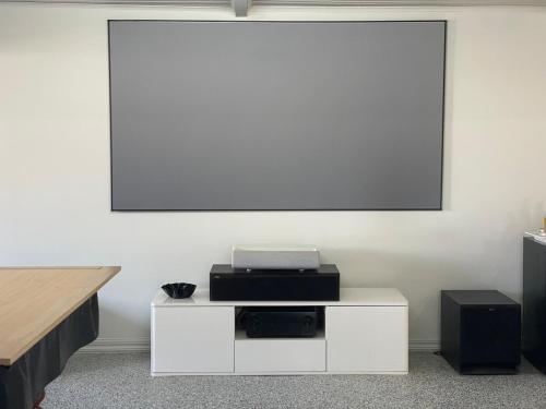 a white entertainment center with a screen on a wall at The Orchard Guesthouse in Palmwoods