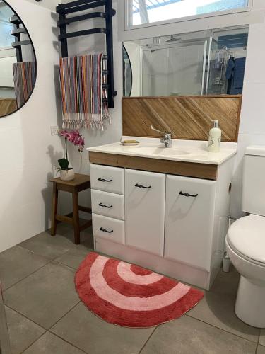 a bathroom with a sink and a toilet and a mirror at The Orchard Guesthouse in Palmwoods