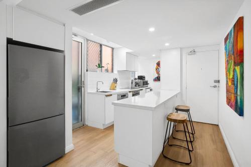 a kitchen with white cabinets and a black refrigerator at Cosy Apartment close to Manly Beach in Sydney