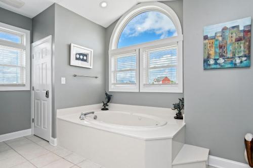 a white bathroom with a tub and an arched window at Luxury Sands in Emerald Isle