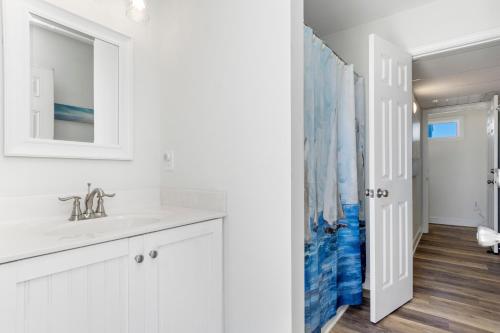 a white bathroom with a sink and a mirror at Nautical Skies in Indian Beach