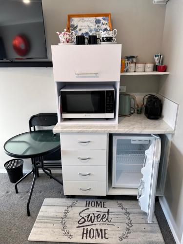 a white desk with a microwave and a chair at The Studio Haven in Hamilton