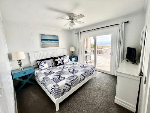 a bedroom with a bed and a television and a balcony at Carolina Clipper West in Emerald Isle