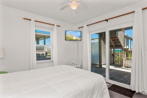 a white bedroom with a bed and a balcony at Carolina Clipper East in Emerald Isle