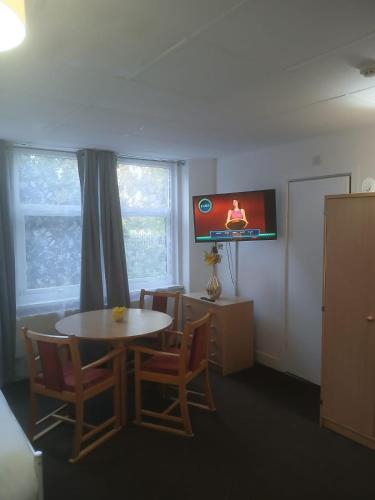 a room with a table and chairs and a tv at Budget Studio - Central Gosport with Free Parking in Gosport