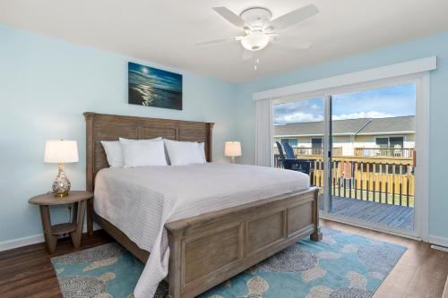 a bedroom with a bed and a balcony at Pine Knoll Townes 126 by Emerald Isle Realty in Pine Knoll Shores