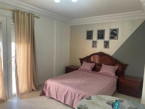 Un dormitorio con una cama con sábanas rosas y almohadas rosas. en Appartement calme et lumineux, en Sousse