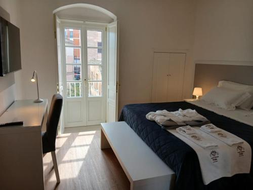 Un dormitorio con una cama y una mesa y una ventana. en Antica Dimora Petito, en Matera