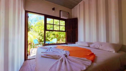 Una cama grande en una habitación con una ventana grande. en Container Eco Suítes, en Cabo Frío