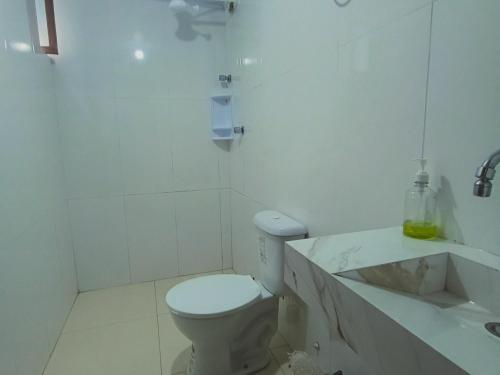 a white bathroom with a toilet and a sink at Apartamento Próximo a Pituba in Itacaré