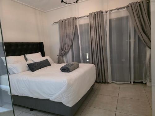 Un dormitorio con una cama grande con sábanas y almohadas blancas. en Aurora Executive Stay In Waterfall City, en Midrand