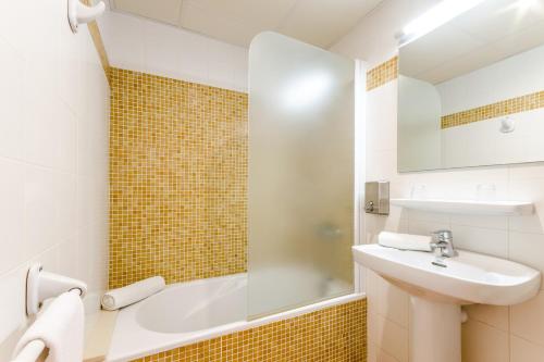 a bathroom with a sink and a mirror and a tub at Apartamentos Blancala in Cala Blanca