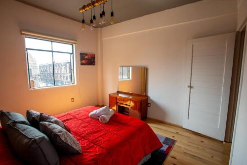 a bedroom with a red bed and a desk and a window at Experience the Magic of the Historic Center from Your Own Balcony in Mexico City