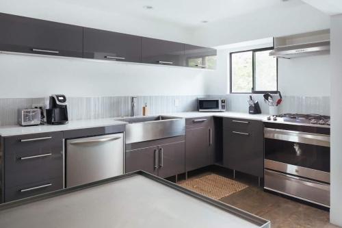 a kitchen with gray cabinets and stainless steel appliances at Hotel El Cid by AvantStay in Palm Springs