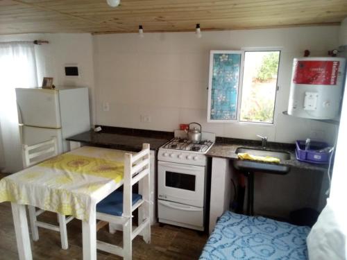 a kitchen with a table and a stove and a refrigerator at Luli 1 in Villa Gesell