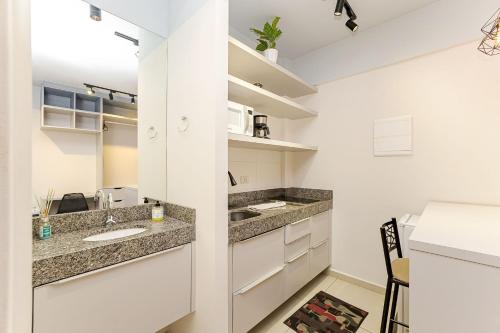 a kitchen with white cabinets and a sink at Eco Smart - Ecoville | Gonzaga Stays in Curitiba