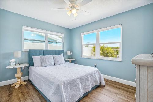 a blue bedroom with a bed and two windows at 106 La Riviere Rd in Cocoa Beach