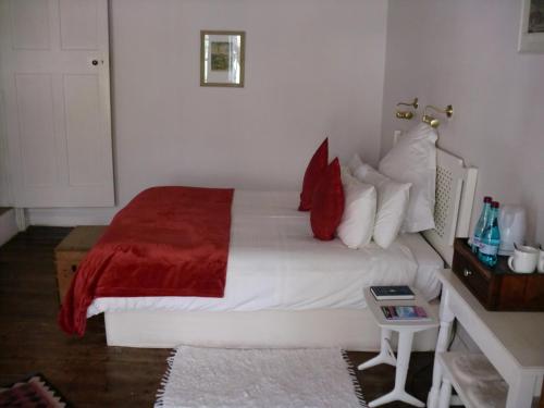 a bedroom with a white bed with red pillows at The Barracks in Colesberg
