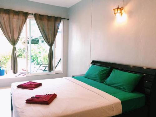uma cama com lençóis verdes e brancos e uma janela em Maehaad Garden Inn em Mae Haad