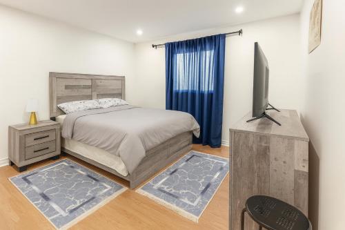 Un dormitorio con una cama y un televisor de pantalla plana. en Comfy & Spacious 4BR Family Home with Free Parking, Laundry, BBQ! 10 Min Walk to Headwaters Hospital, 5 Min Drive to Mount Alverno Luxury Resorts, Ideal for Medical, Vacation or Work Stays!, en Orangeville