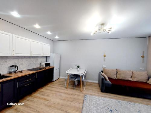 a kitchen and living room with a couch and a table at Уютные апартаменты в ЖК Триумф сити in Astana