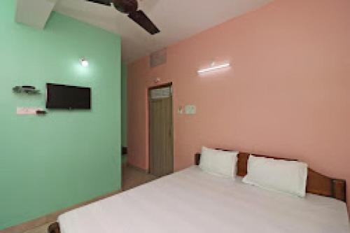 Un dormitorio con una cama y un televisor en la pared. en Hotel O sea palace, en Cossipore