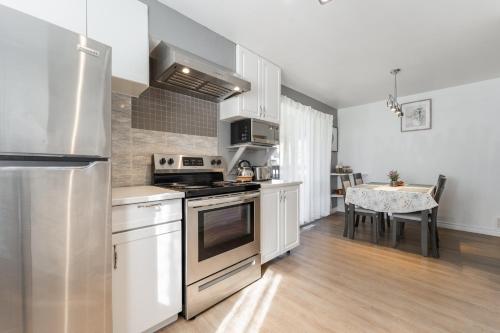 a kitchen with stainless steel appliances and a table at Cozy Family Home Near Montreal in Brossard