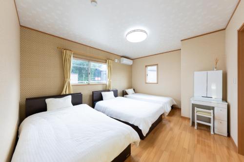 a room with two beds and a tv at GuestHouse　YOU&I in Fujikawaguchiko